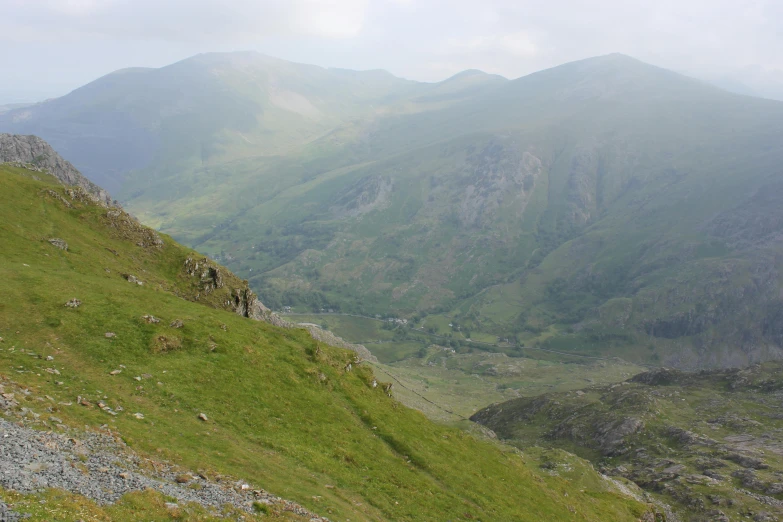 a mountain side covered in lots of green grass