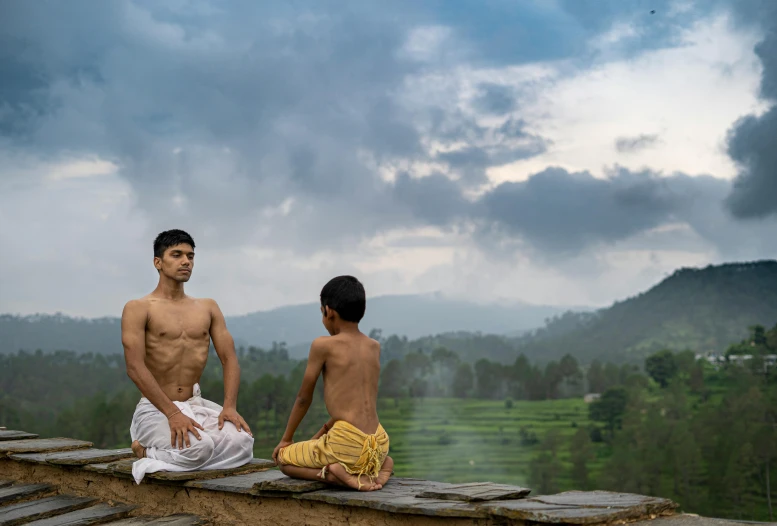 two young men sitting on a stone wall