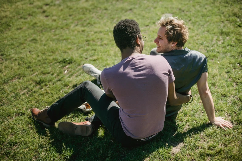 two men sitting in the grass looking at soing