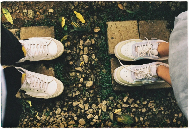 two pairs of feet sitting on concrete outside