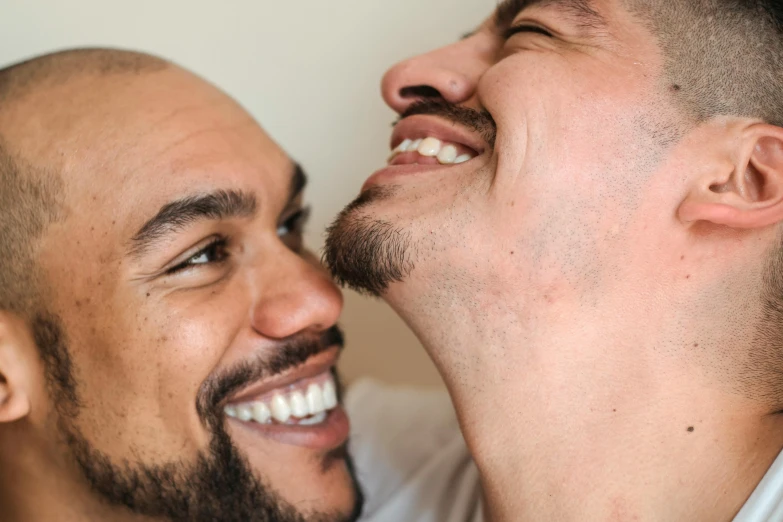 two men smile while one holds his chin on the neck of the other