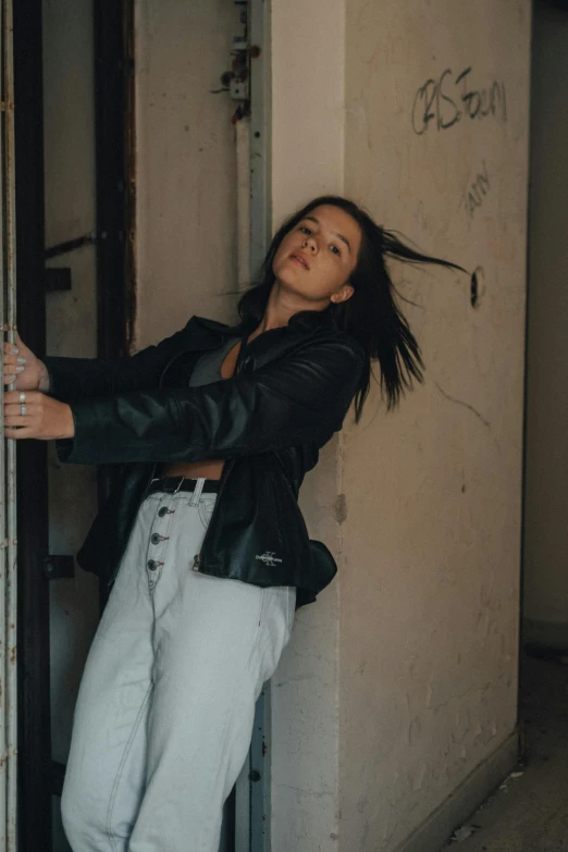 a young woman leaning on the side of a building