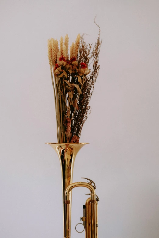 a ss trumpet that has dried flowers on it