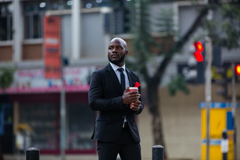 a man in suit and tie holding soing while standing on the street