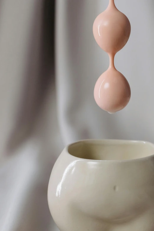 a small white bowl holding two pink, ceramic objects