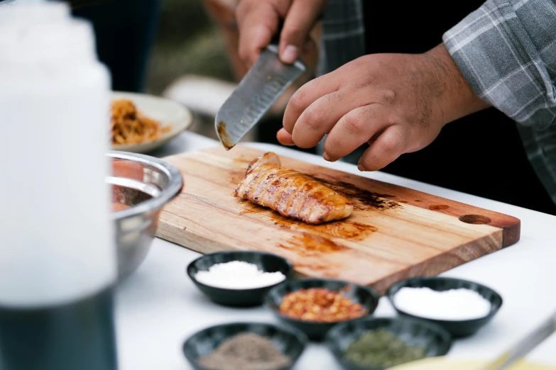 a person is chopping salmon on a wooden  board