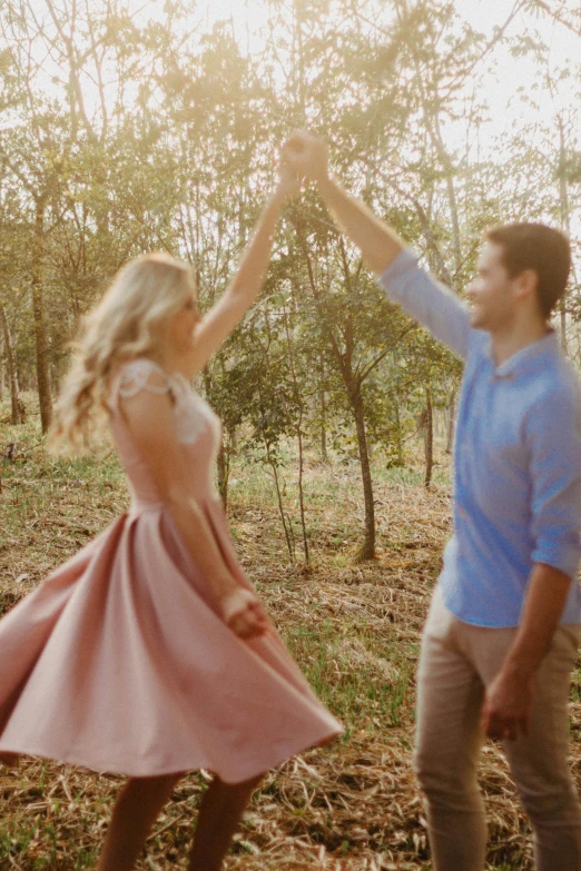 a man and woman standing in a forest, holding hands