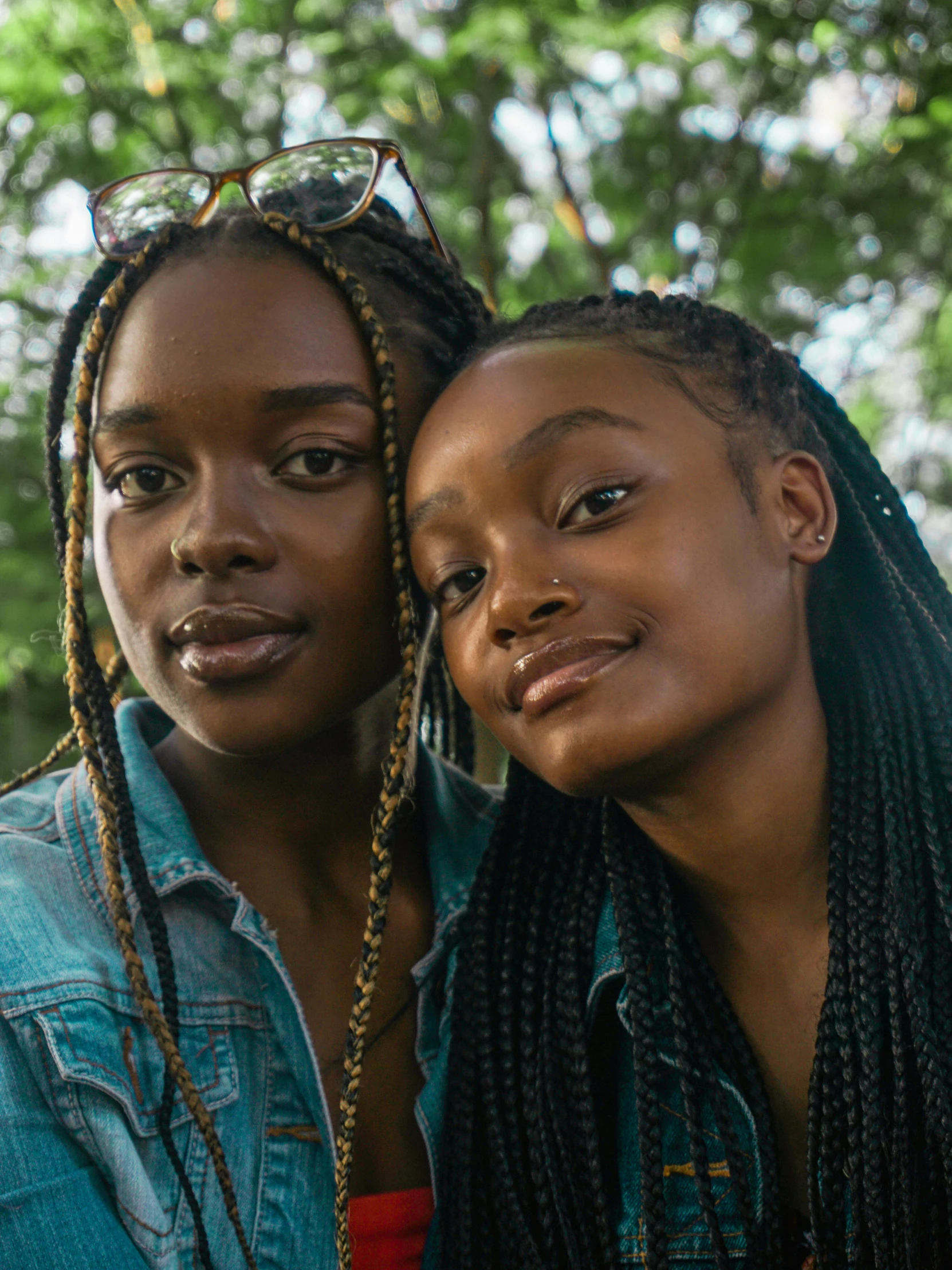 two young women standing together outside in the forest