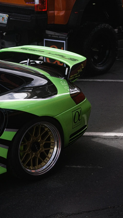 a green race car sitting in front of a truck