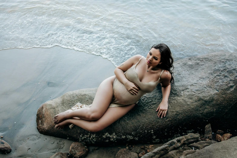 a woman is posing on a rock near the water