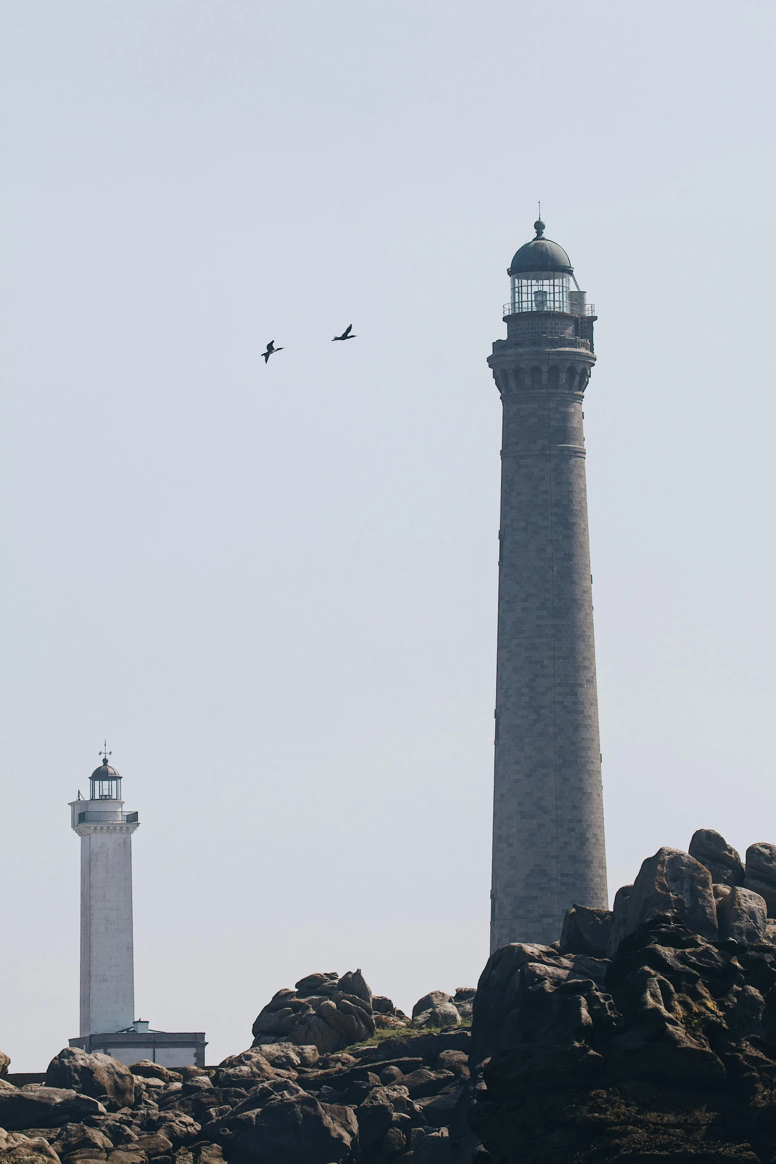 the two light towers are built high on the rocky shore