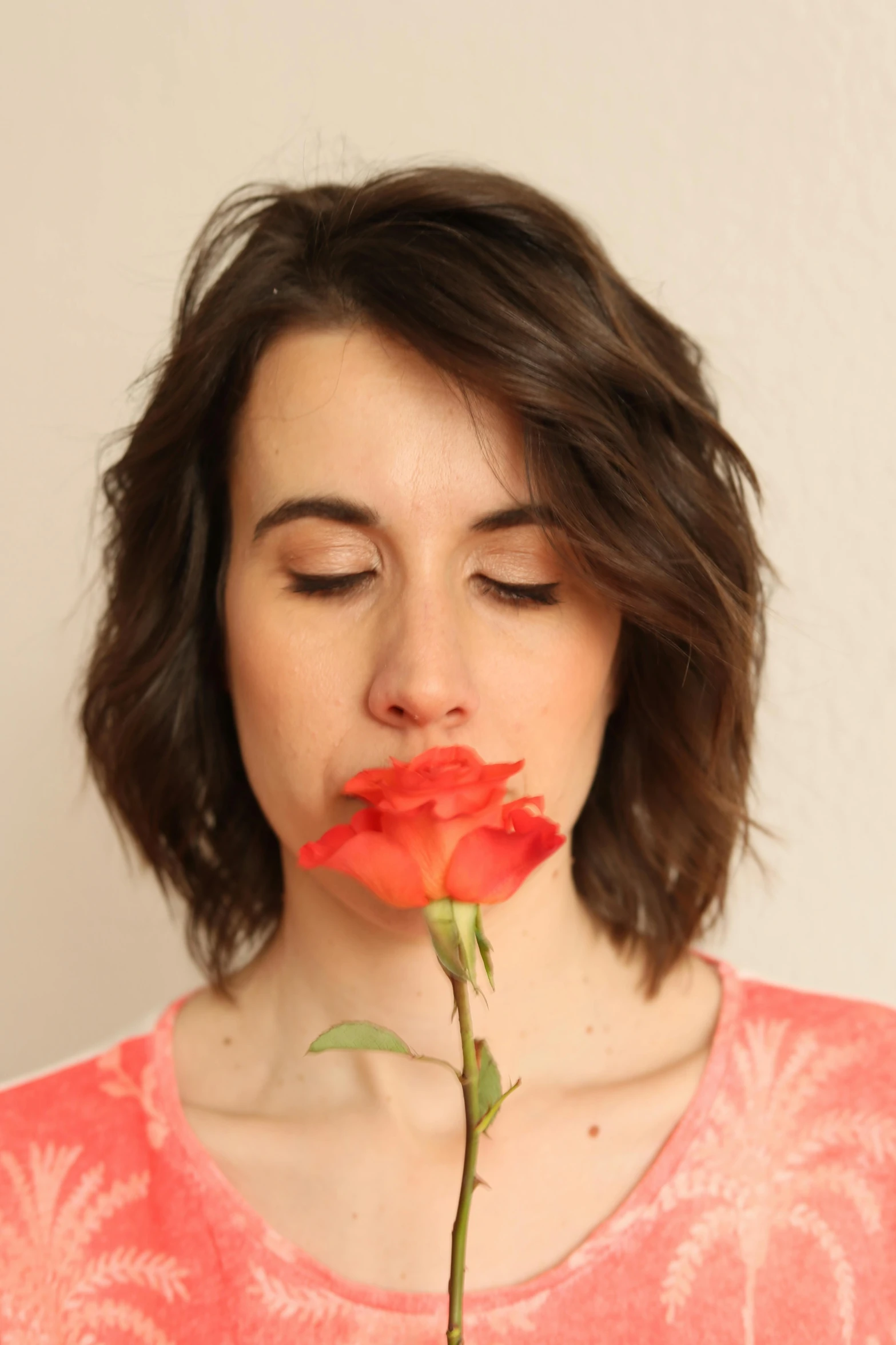 a person holding up a red rose to their mouth