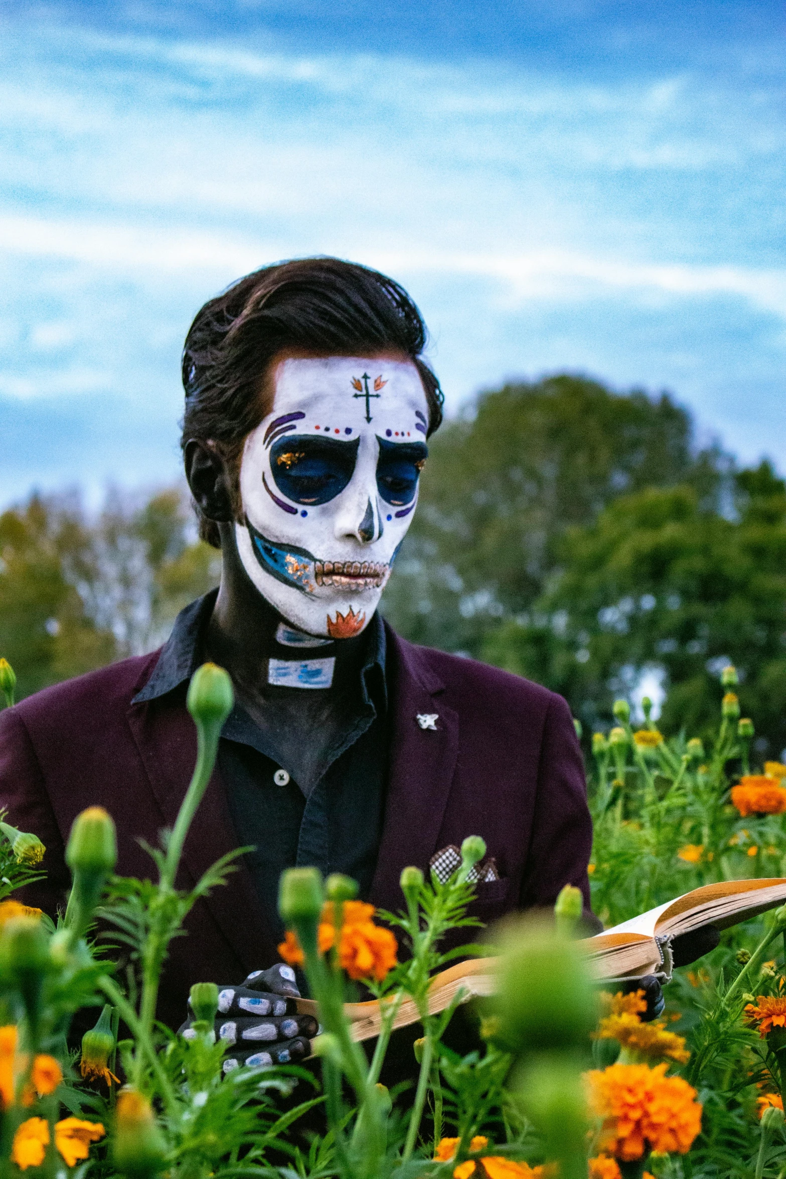 a man with skull paint on is standing in a field full of orange flowers