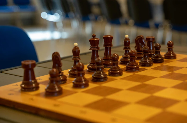 a chess board with pieces on top and chairs behind it