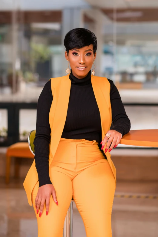 the beautiful woman is sitting on a table with an orange pants