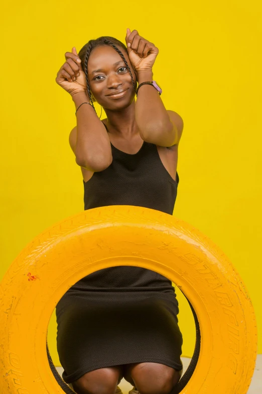 a woman wearing black, holding her arms above her head and sitting in a yellow circle