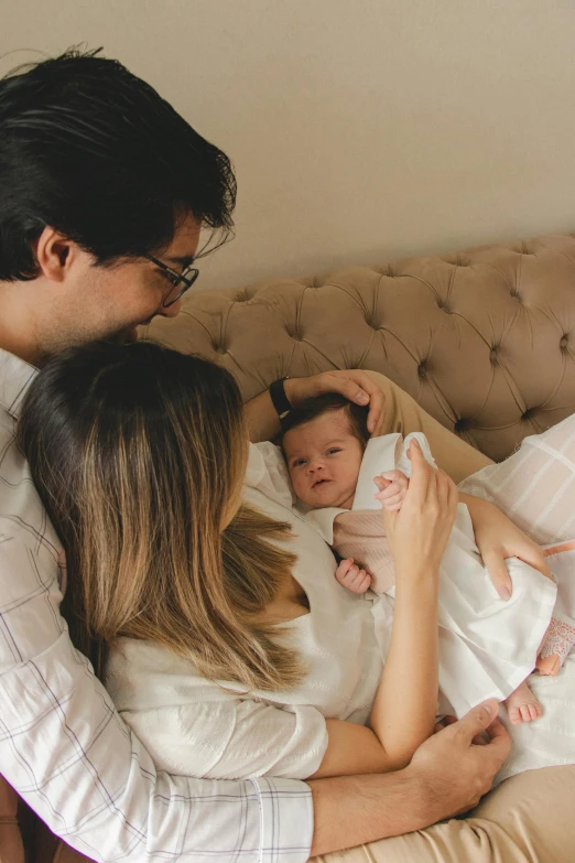 a mom holds a baby while the man sits down to his left