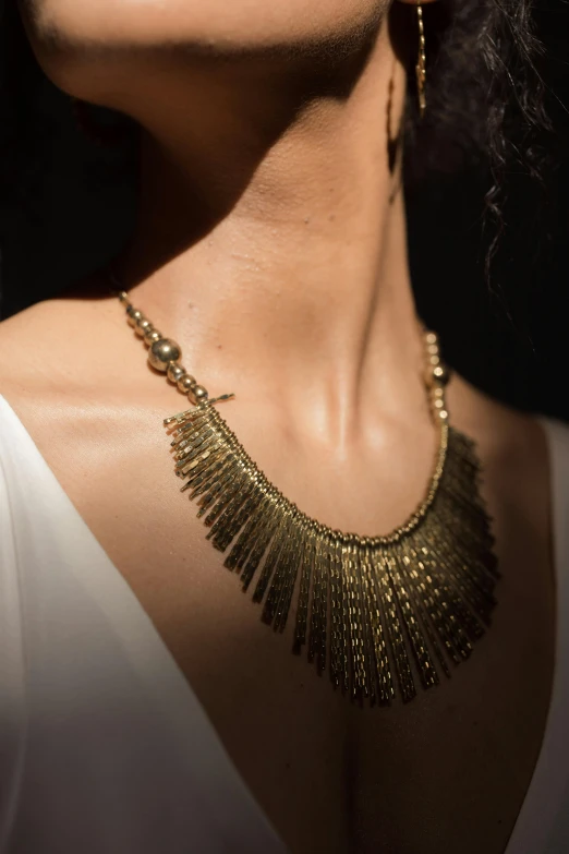 a woman wearing an elaborate gold necklace on her neck