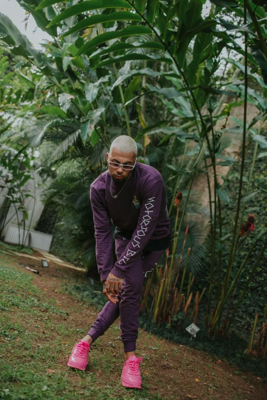 a man standing in the grass with pink shoes