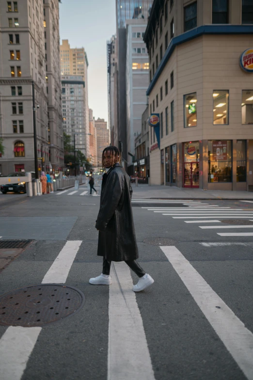a person in black coat crossing street next to building