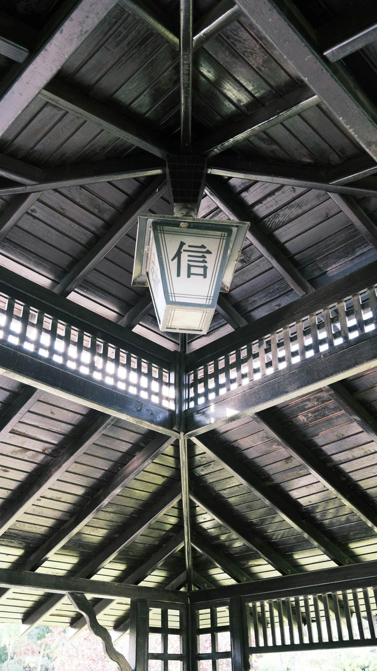 an indoor structure with a metal roof and a decorative light fixture on the ceiling