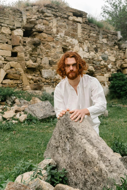 a man sitting on a rock with one foot on his knee