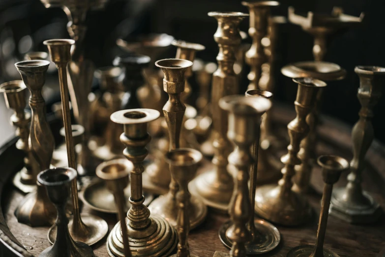 a pile of metallic candlesticks lined up against a table