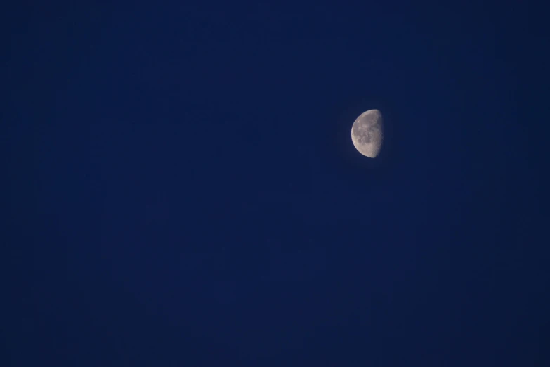 the moon in a dark blue sky with only a few stars