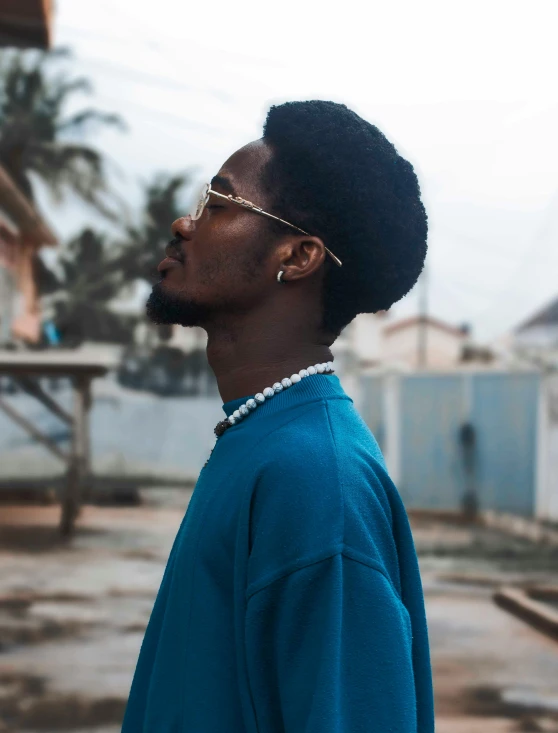 an african american man with a blue sweater and gold eyeglasses