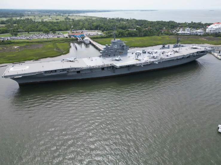 a large naval ship in the water by a dock