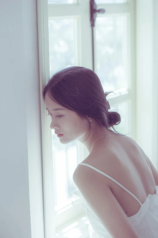 young asian woman in white dress looking out window