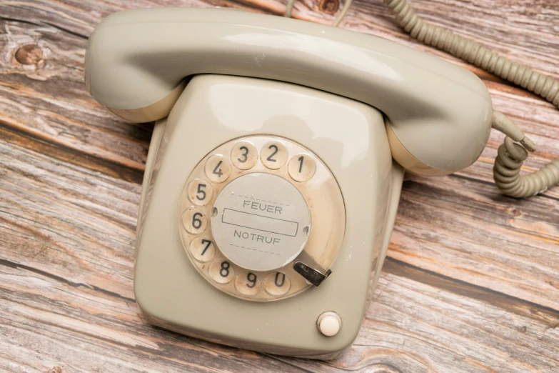 an antique white rotary telephone on a wooden surface