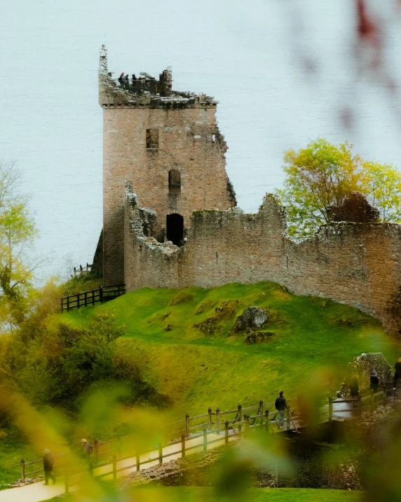 an old castle with its grass roof is sitting on a hill