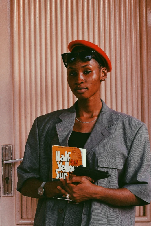 a young man standing in front of a wall holding a book