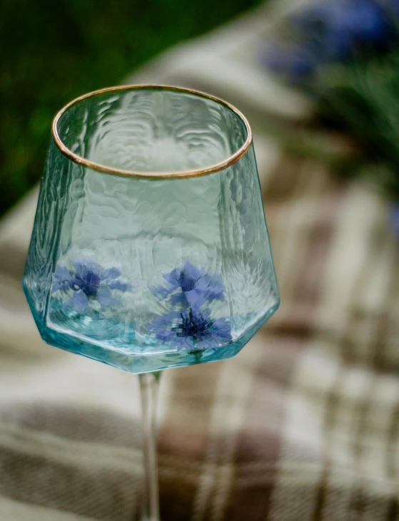 a wine glass sitting on a table next to a checkered cloth