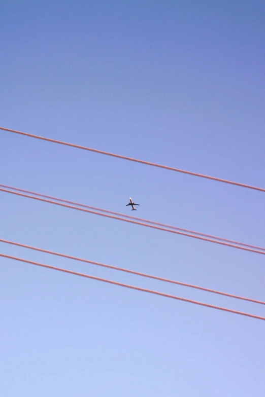 an airplane in the sky between two red wires