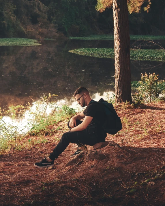 a man sits on a rock in front of a body of water