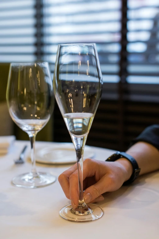 a hand is holding the tip of an empty wine glass