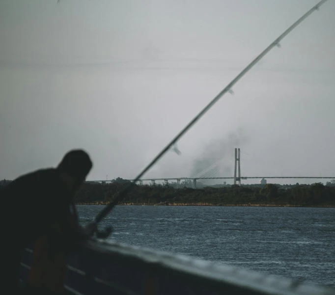 a man standing next to the ocean near water with his fishing pole in hand