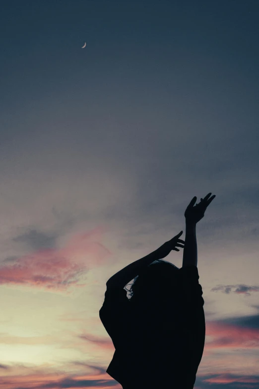 a person standing in the middle of a field and reaching up with a kite