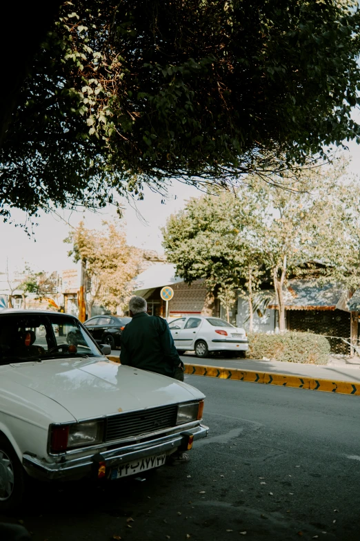 a man in green is standing beside a car