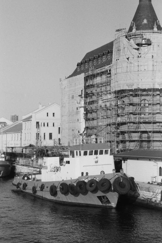 a construction boat is in front of a big building