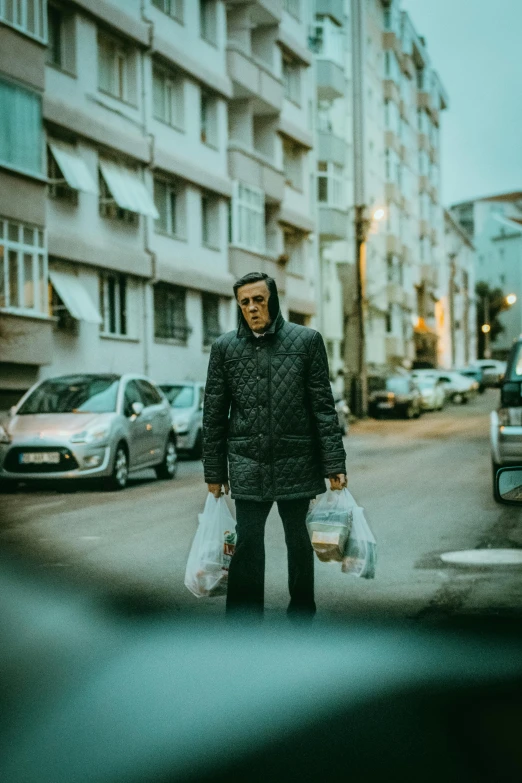 the man is holding bags standing on the street