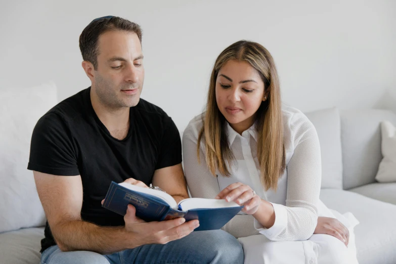 a man and woman reading a book on the couch