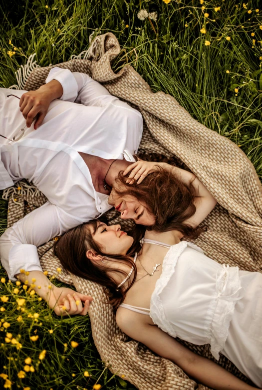 two women lay on a blanket in the grass