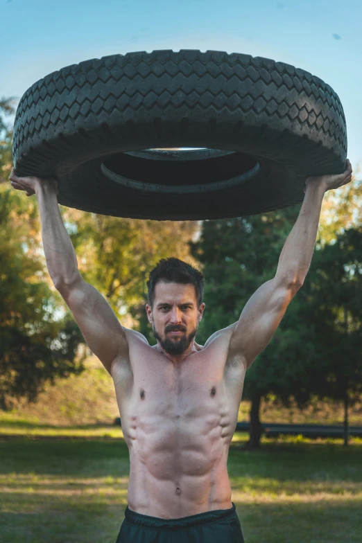 a man holding up a big tire over his head