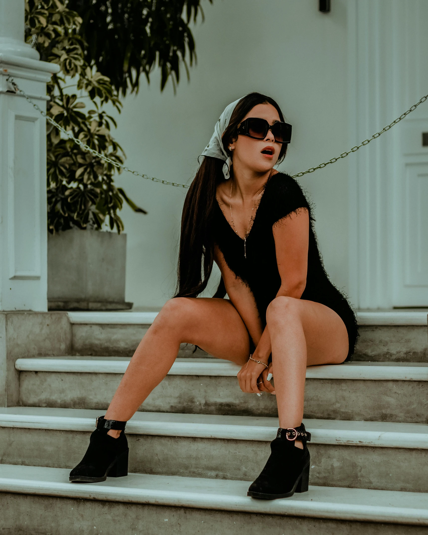 woman sitting on steps wearing high heels and sunglasses