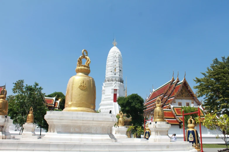 many golden buddha statues with buildings in the background