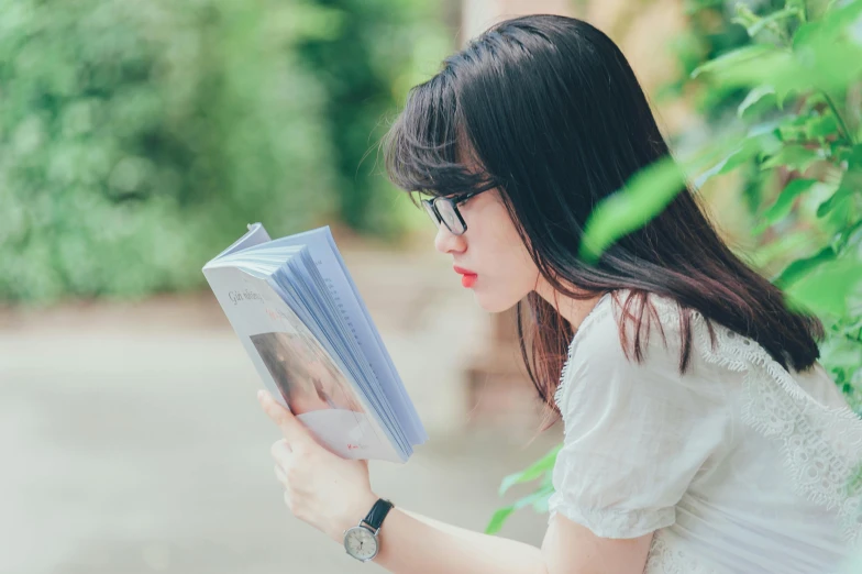 the girl is reading the book outside by the plants