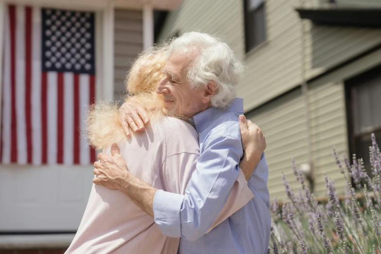 two elderly women standing on a sidewalk, hugging